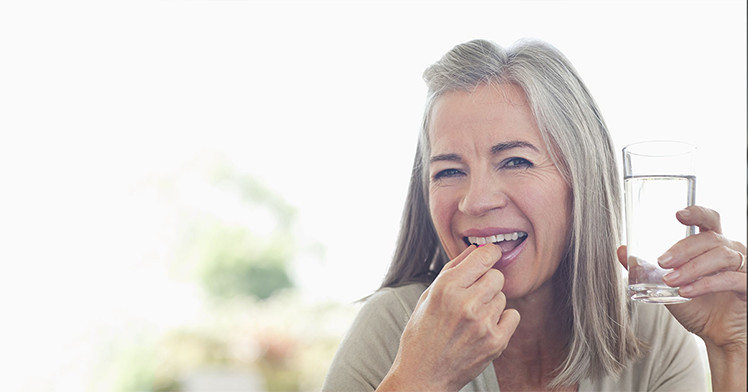 an elder happily taking a vitamin
