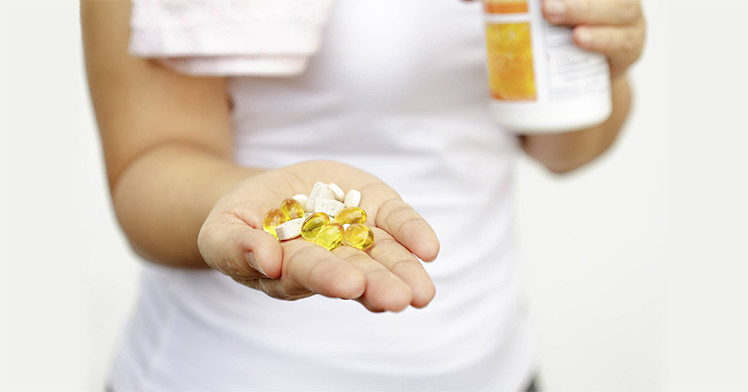 vitamin supplement tablets on a woman's hand